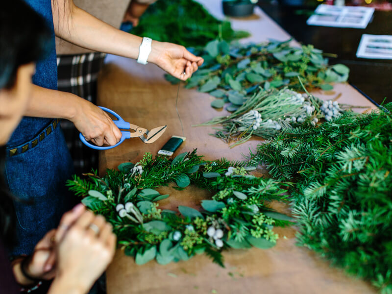 A person adds greenery to their handmade wreath.